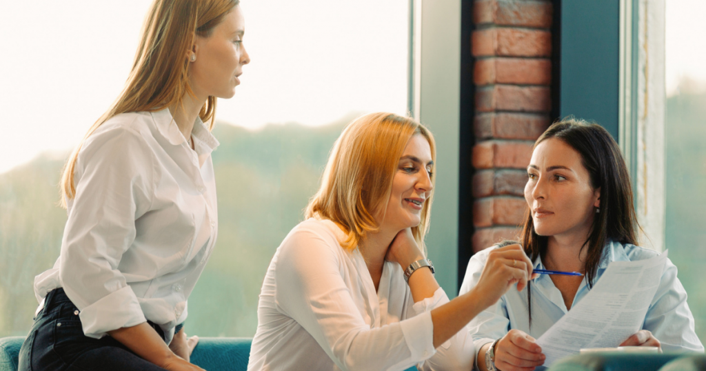 Tre affärskvinnor som har ett möte och granskar papper