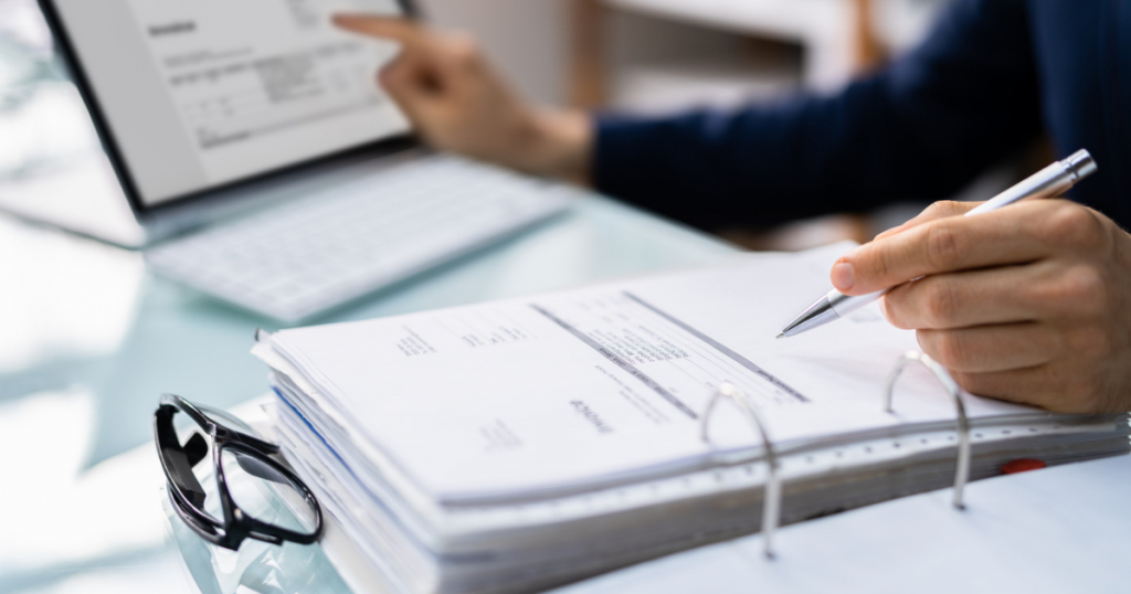 Person som granskar dokument och fakturor vid en bärbar dator