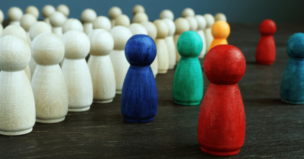 Träfigurer I Olika Färger Står Framför En Publik Av Naturfärgade Figurer