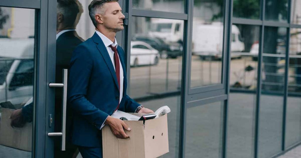 Uppr철rd man i kostym g책r ut med en kartong efter att ha f책tt sparken