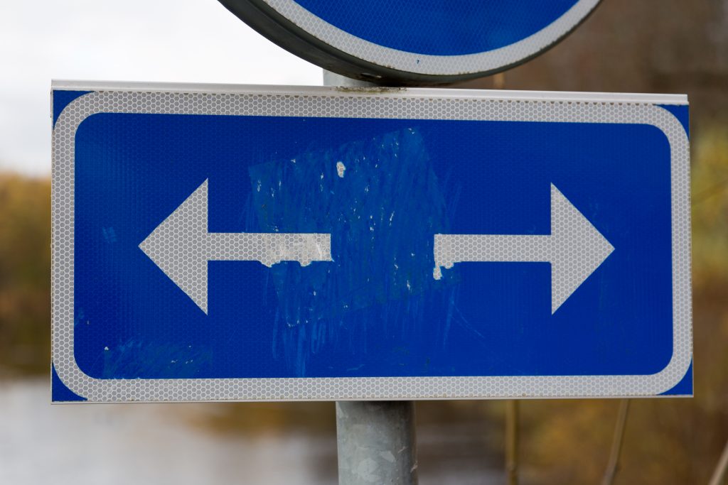 En blå vägskylt med vänster- och högerpilar